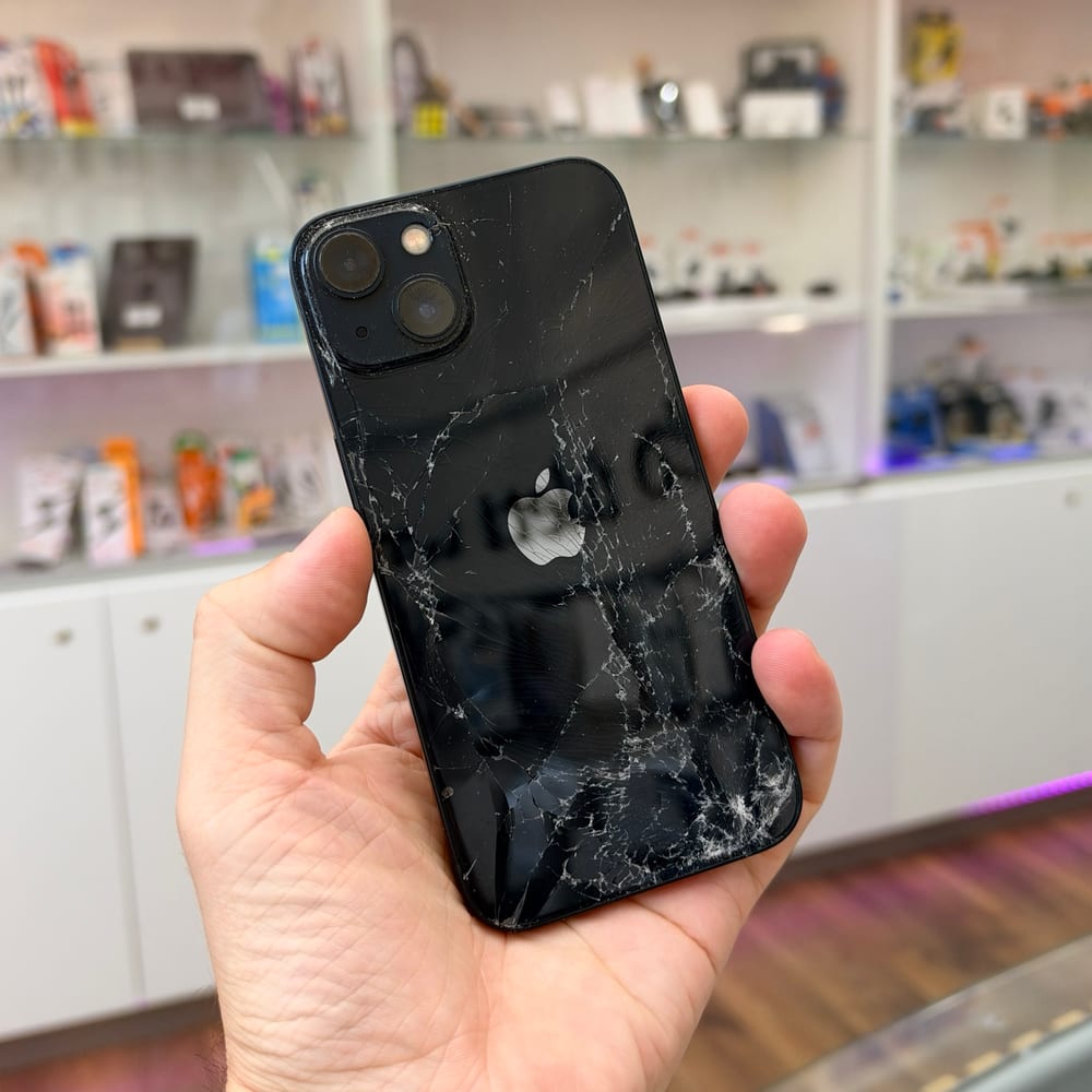 Szilánkosra tört hátlapú fekete iPhone 13 a csere előtt – valódi fotó a NorbiPhone üzletéből